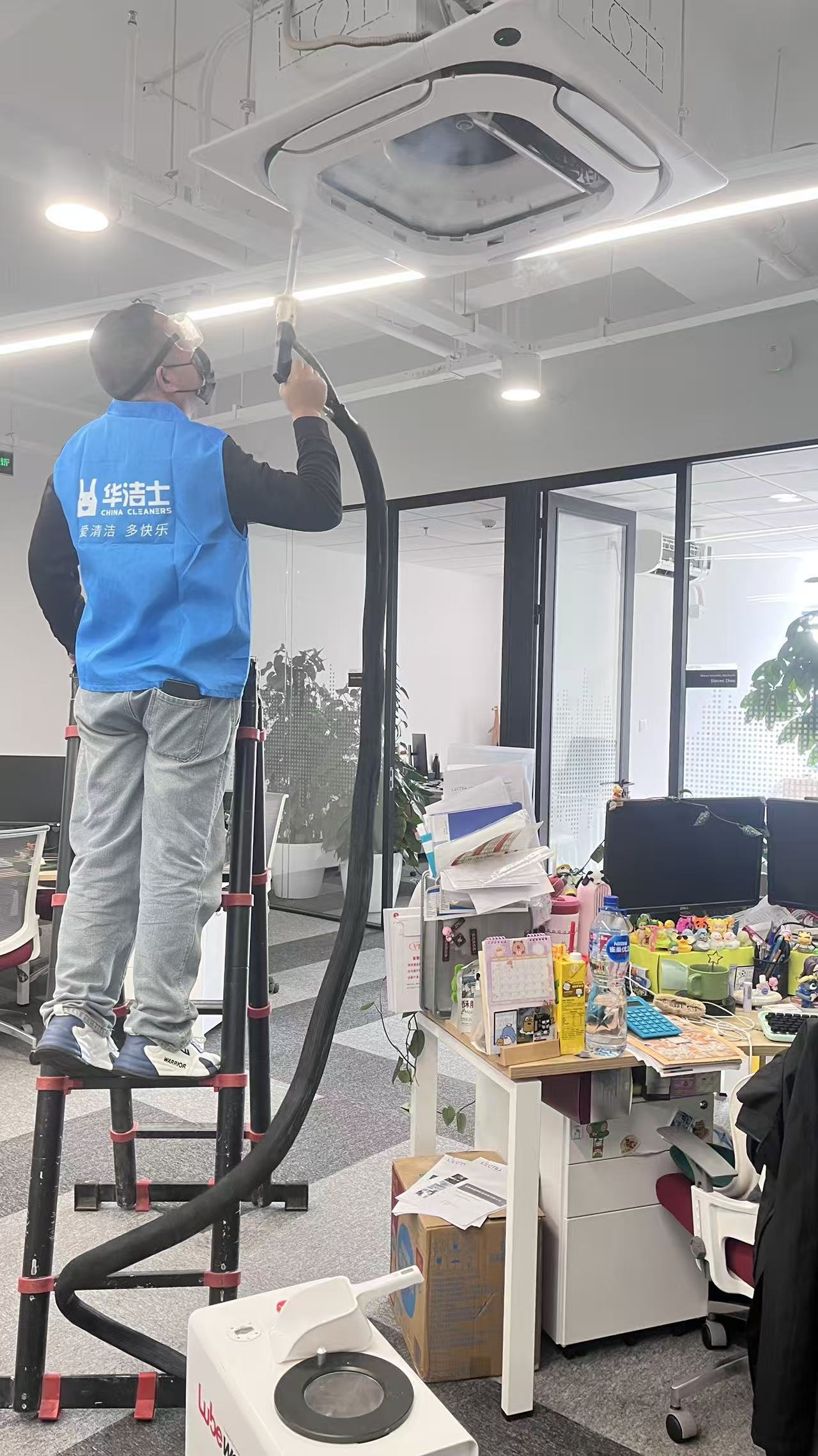 华洁士技师在开放办公区对吸顶式空调进行干冰清洗，佩戴全套防护
