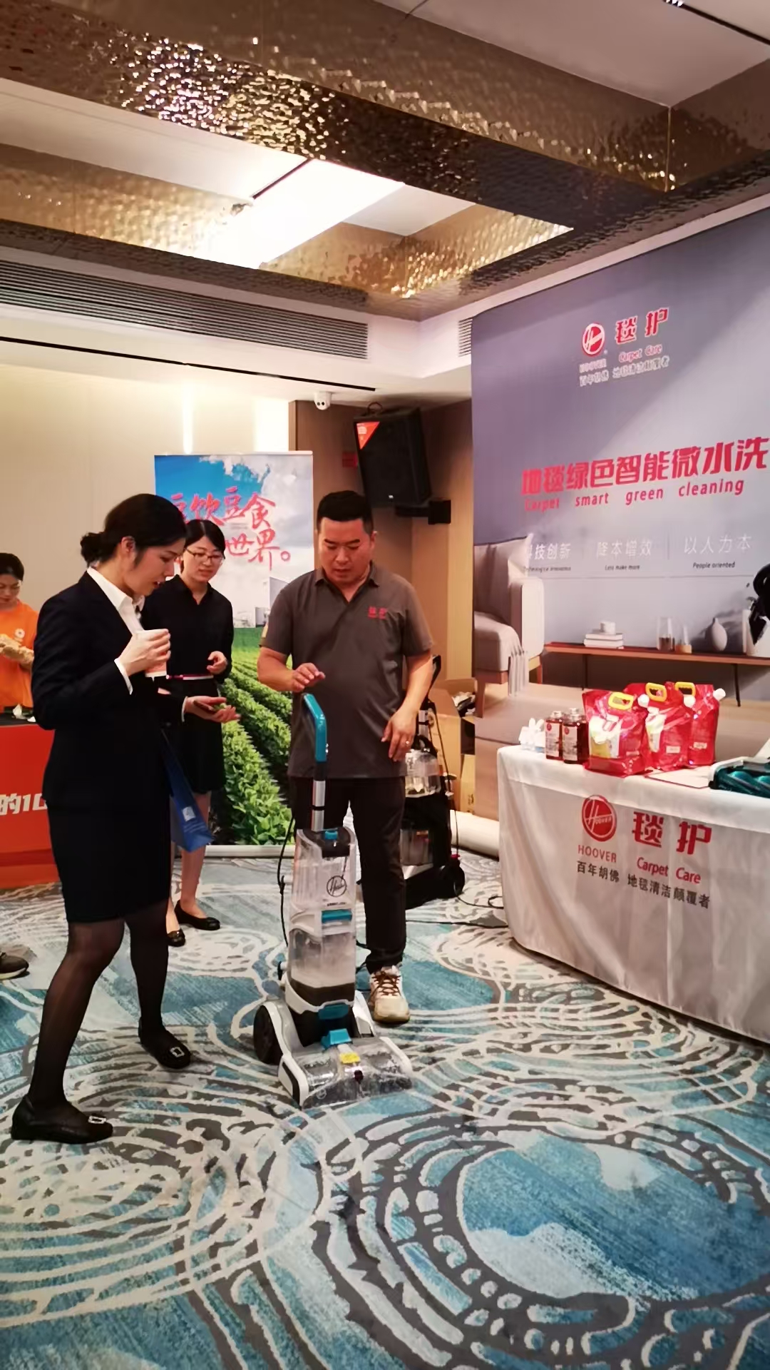 展会现场毯护展位演示胡佛地毯清洗机，观众围观清洗效果