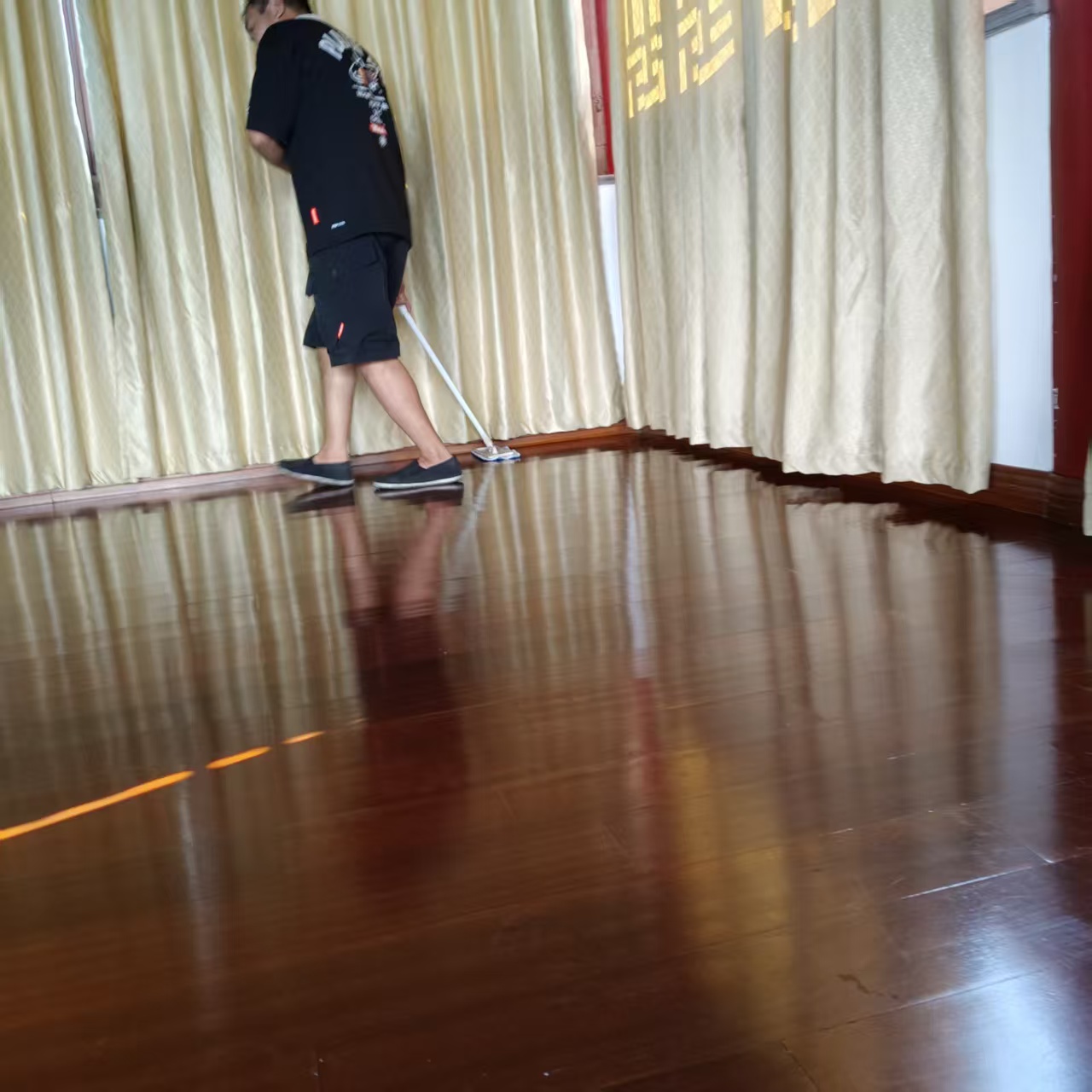 寺院殿堂深色木地板清洗作业，人员分区推进拖洗