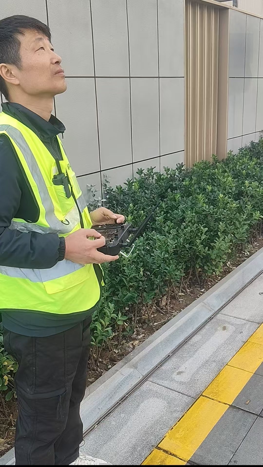 盛捷公寓酒店项目：飞手身穿反光背心手持遥控器，全程目视监控无人机作业状态