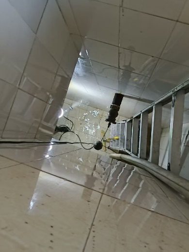 水箱内壁高压水枪冲洗过程：可见水线冲刷痕迹与旋转喷头软管，瓷砖壁面正在被清洗